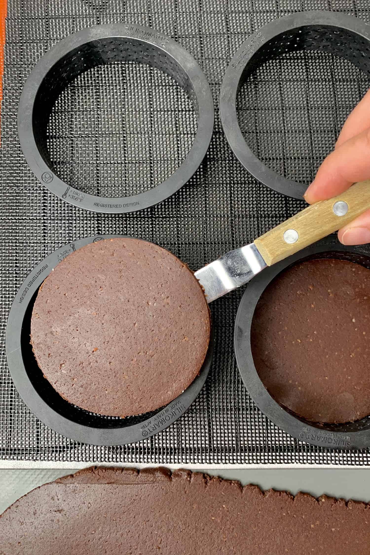 Placing the dough into a tart ring with an offset spatula. 