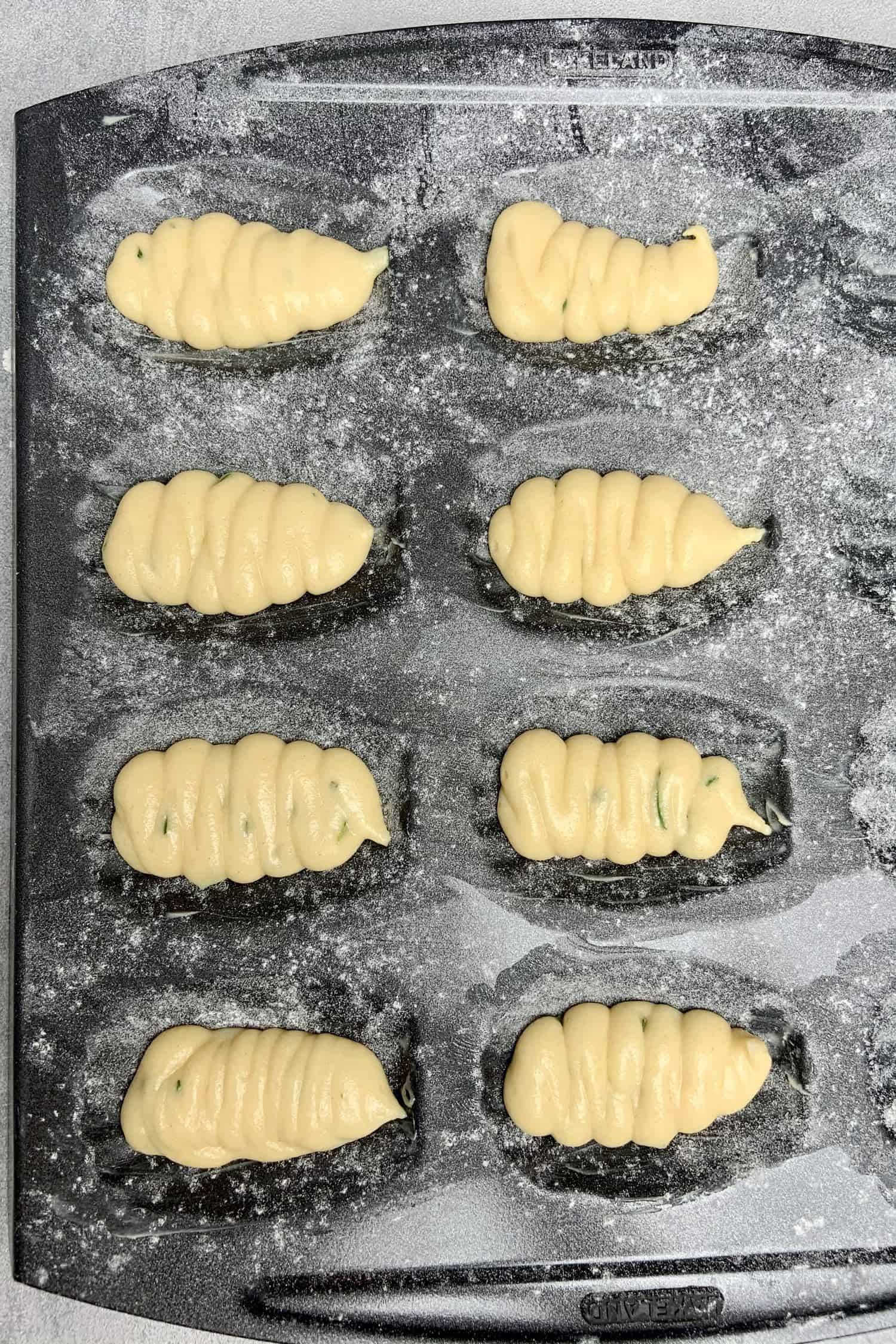 Madeleines piped in the baking tin.