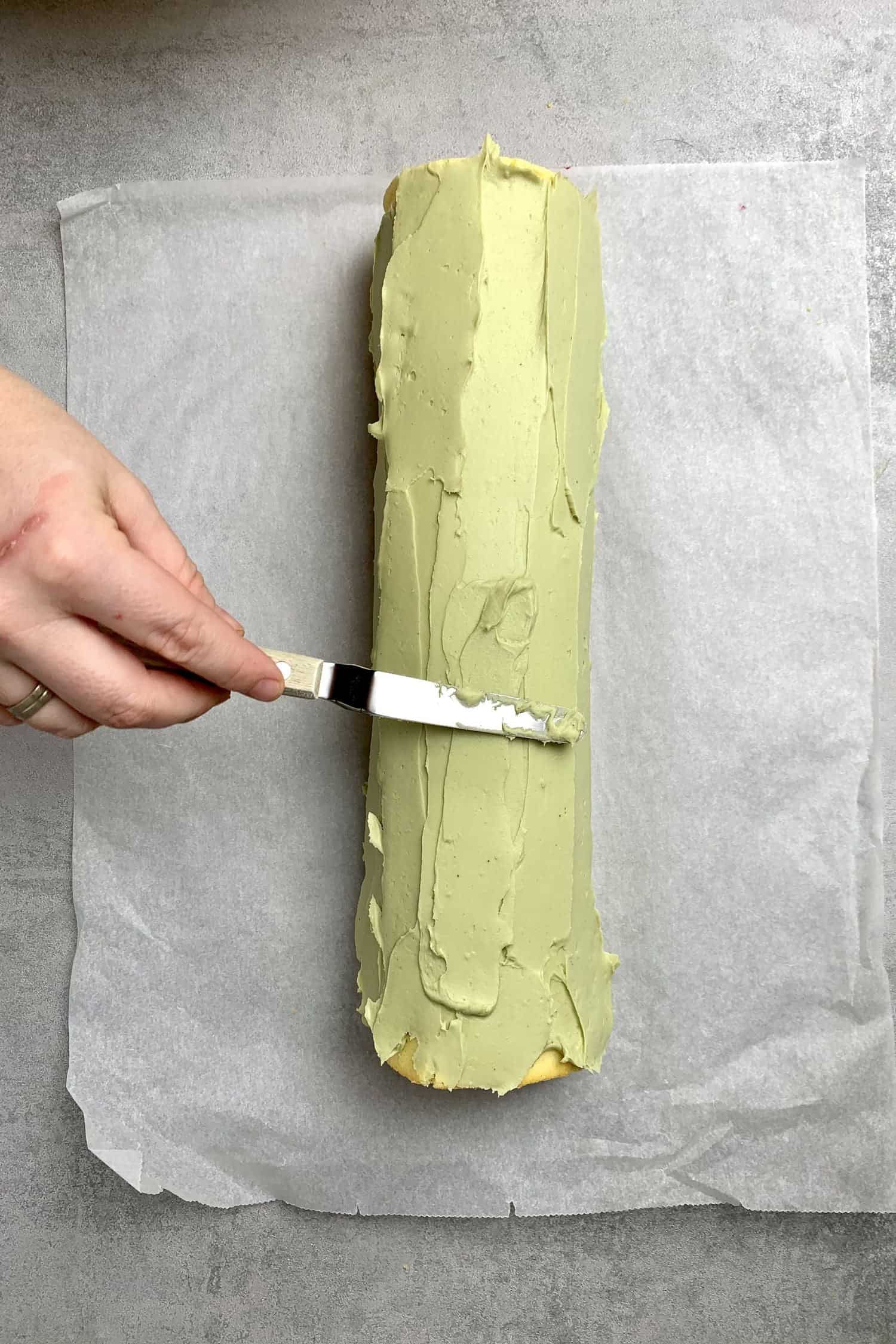 Apply the pistachio frosting on the cake roll.