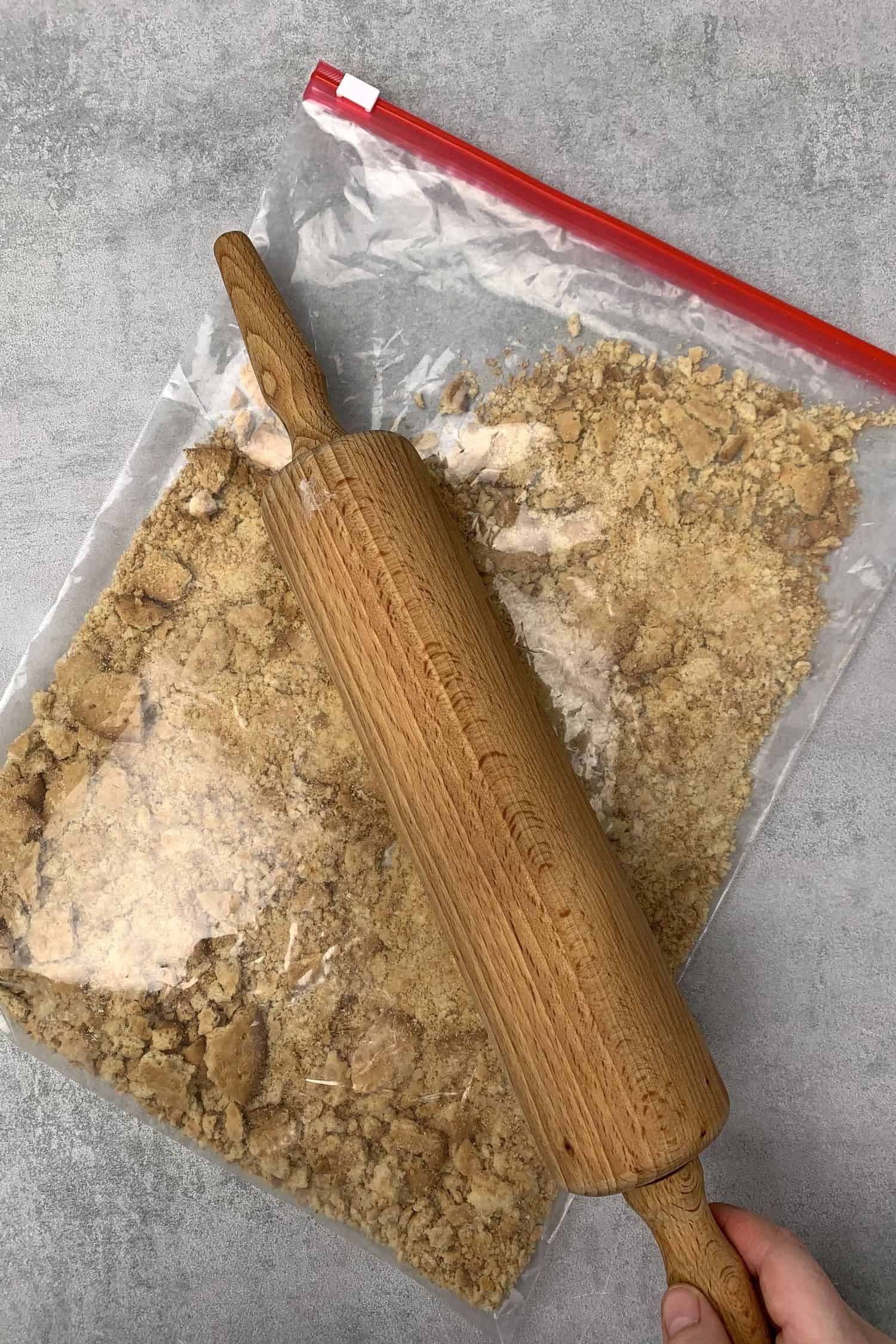 Crushing biscuits in a zipper bag with a rolling pin.