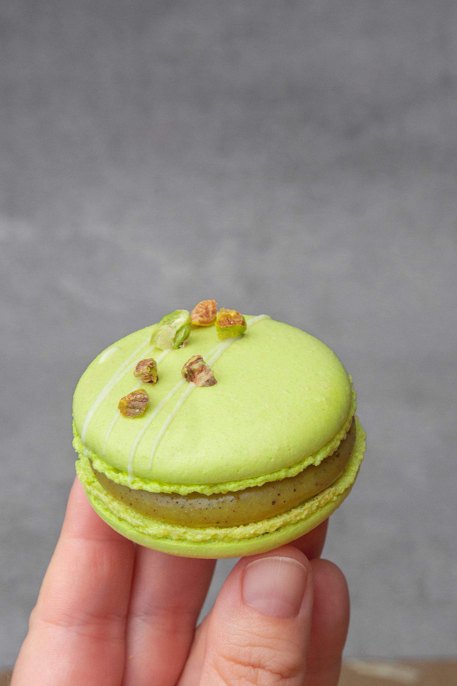 a Pistachio macaron decorated with pistachio and white chocolate.