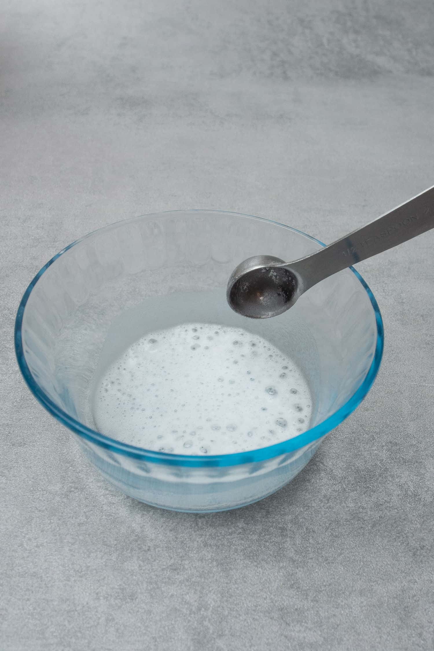 Mixing white vinegar and baking soda in a small bowl.