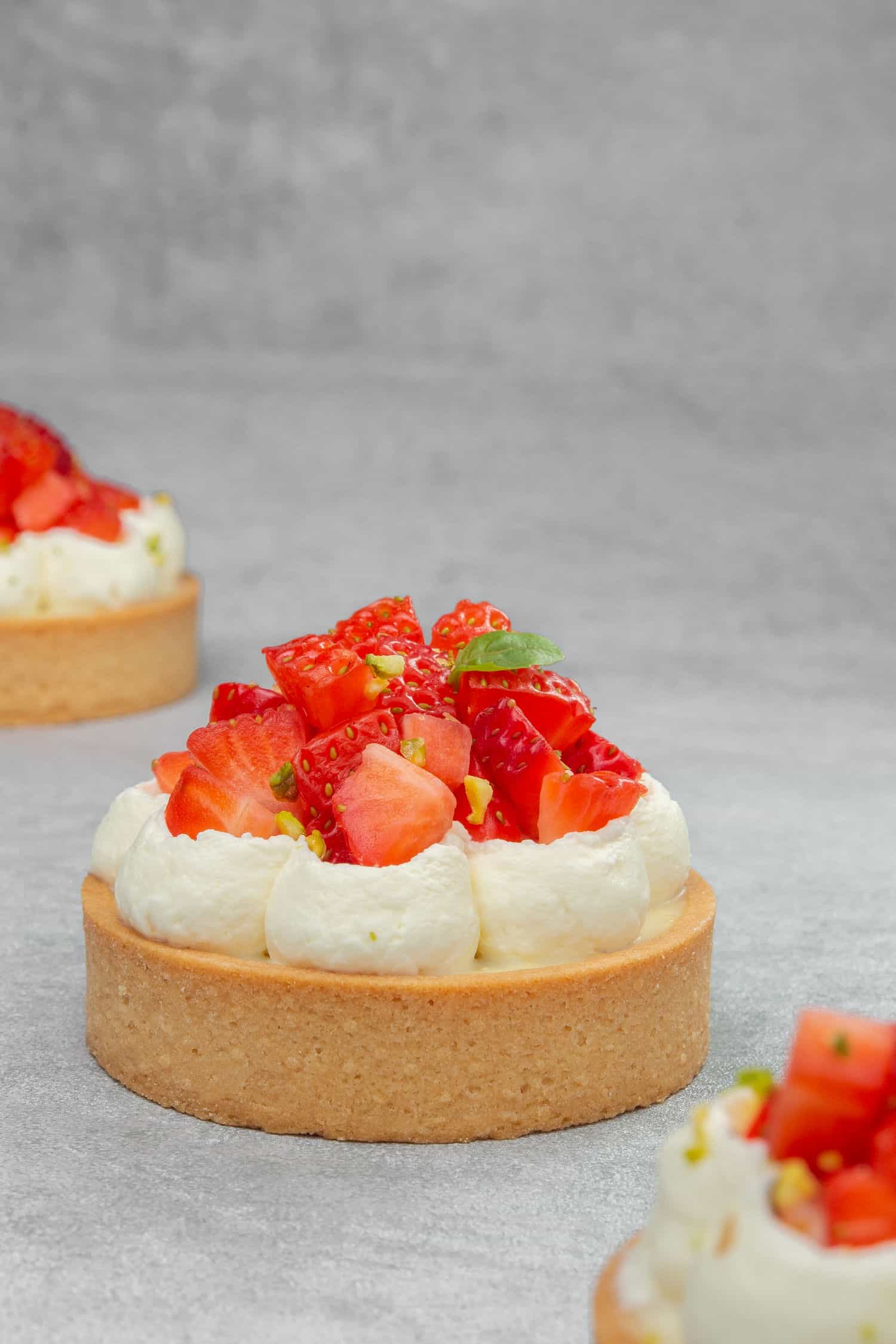 A Strawberry cream tart on a grey surface.