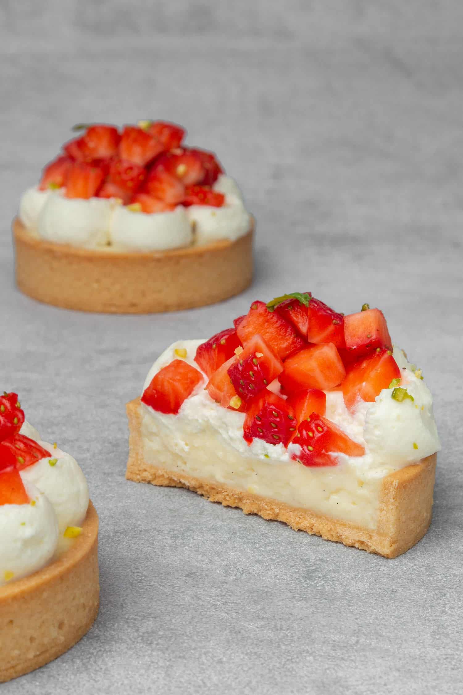 Mini Strawberry tartlets with vanilla custard cut in half, and a whole in the background