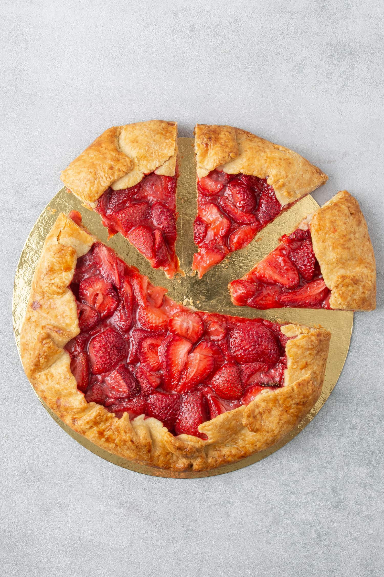 Strawberry Galette on a golden paper plate cut into 4 slices.