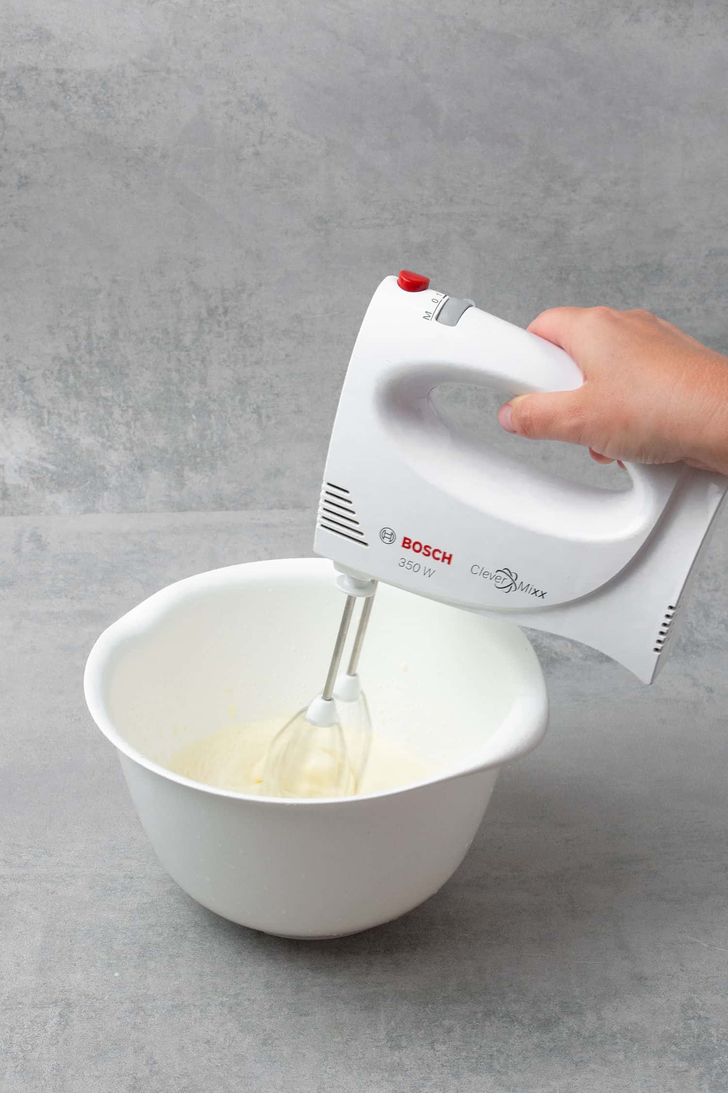 Making whipped cream for decoration in a bowl with an electric hand mixer