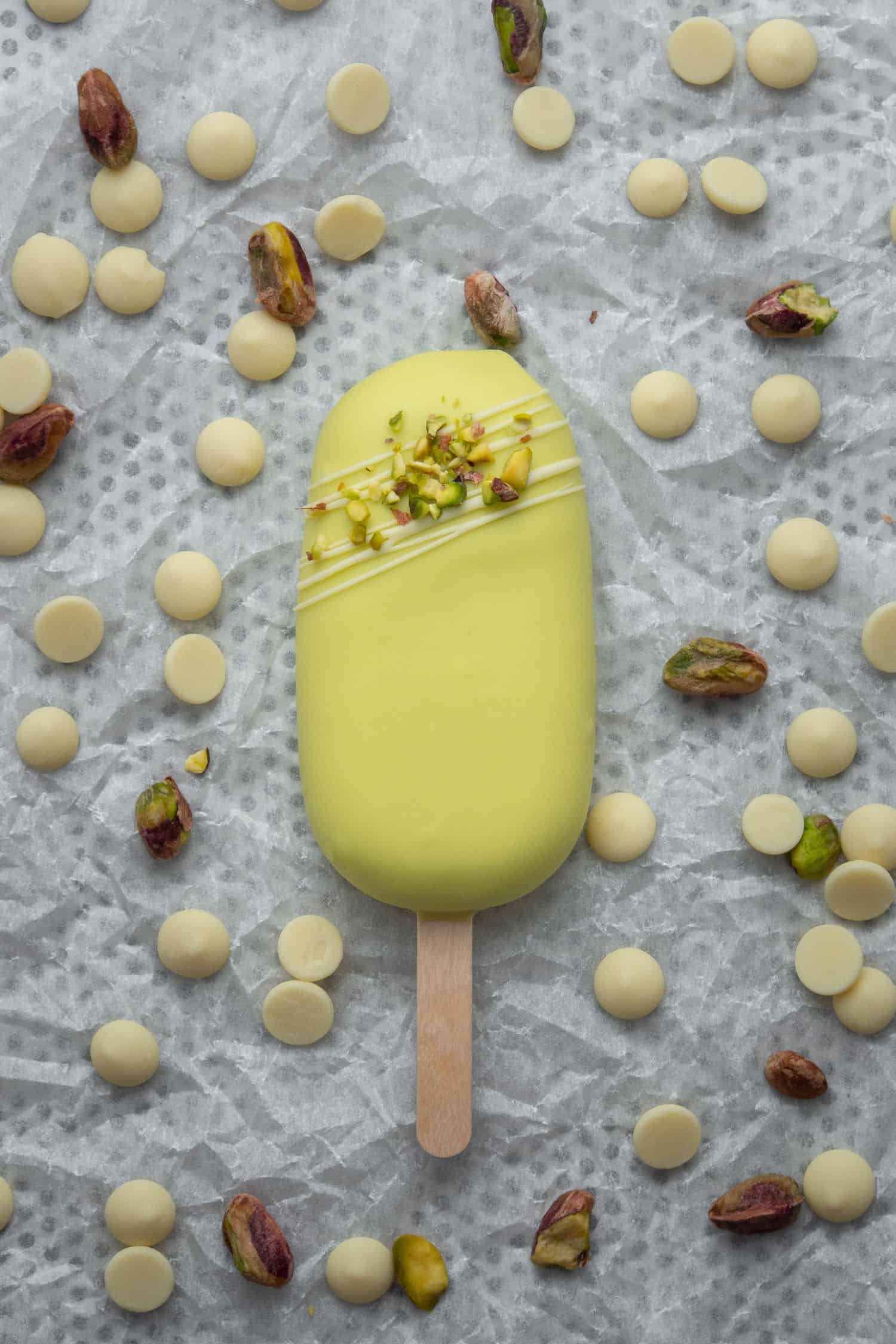 A Pistachio Ice cream bar on a white baking sheet decorated with white chocolate and pistachio.