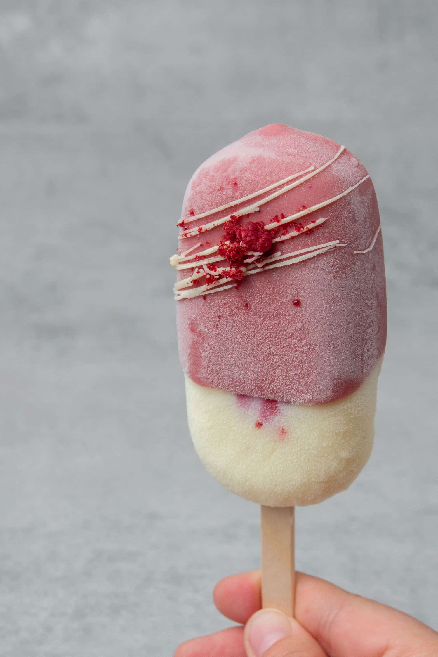 A Ruby chocolate Raspberry ice cream bar with frozen moist on the side. 