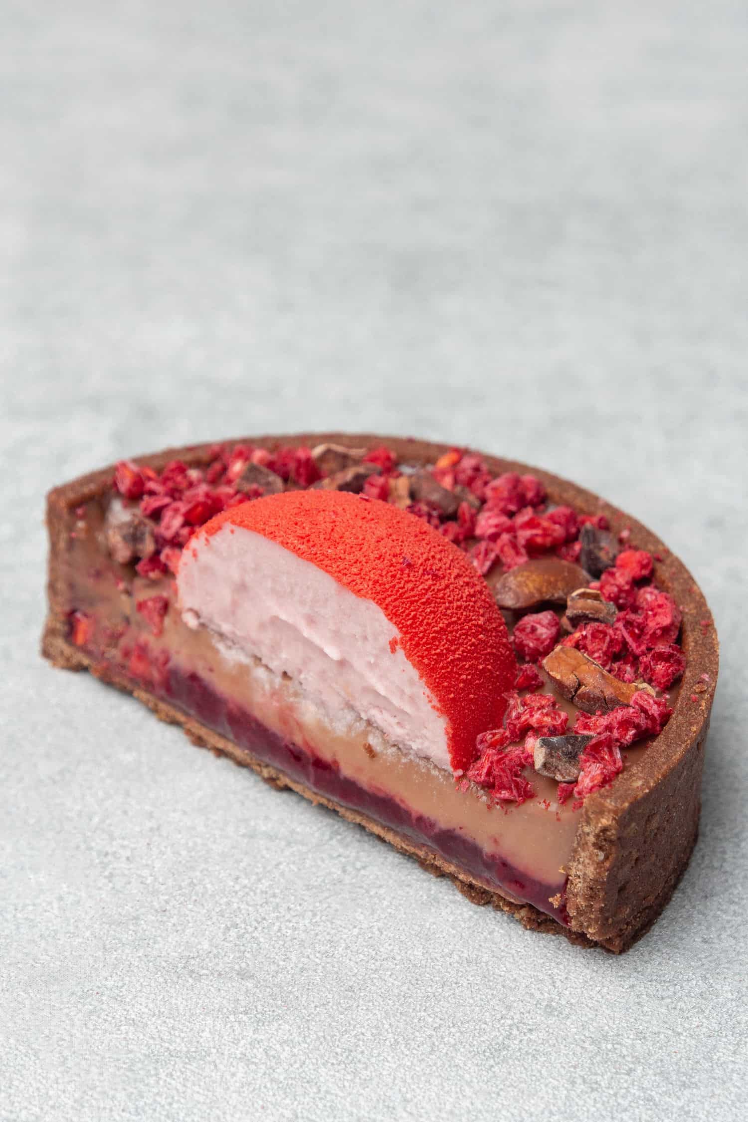 Half Chocolate raspberry tart on a gray table top.