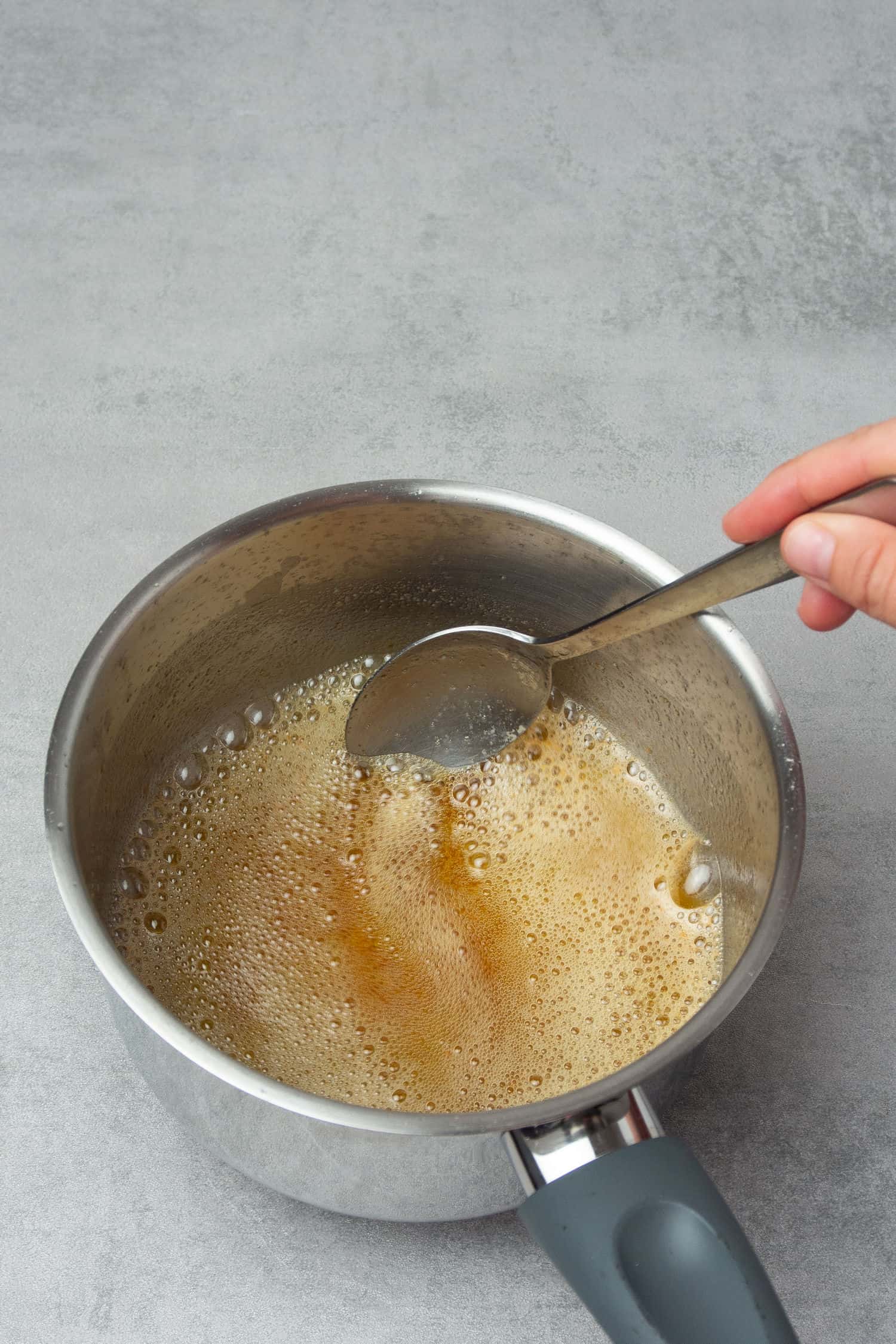 Making brown butter in a small pot and mixing with a spoon.