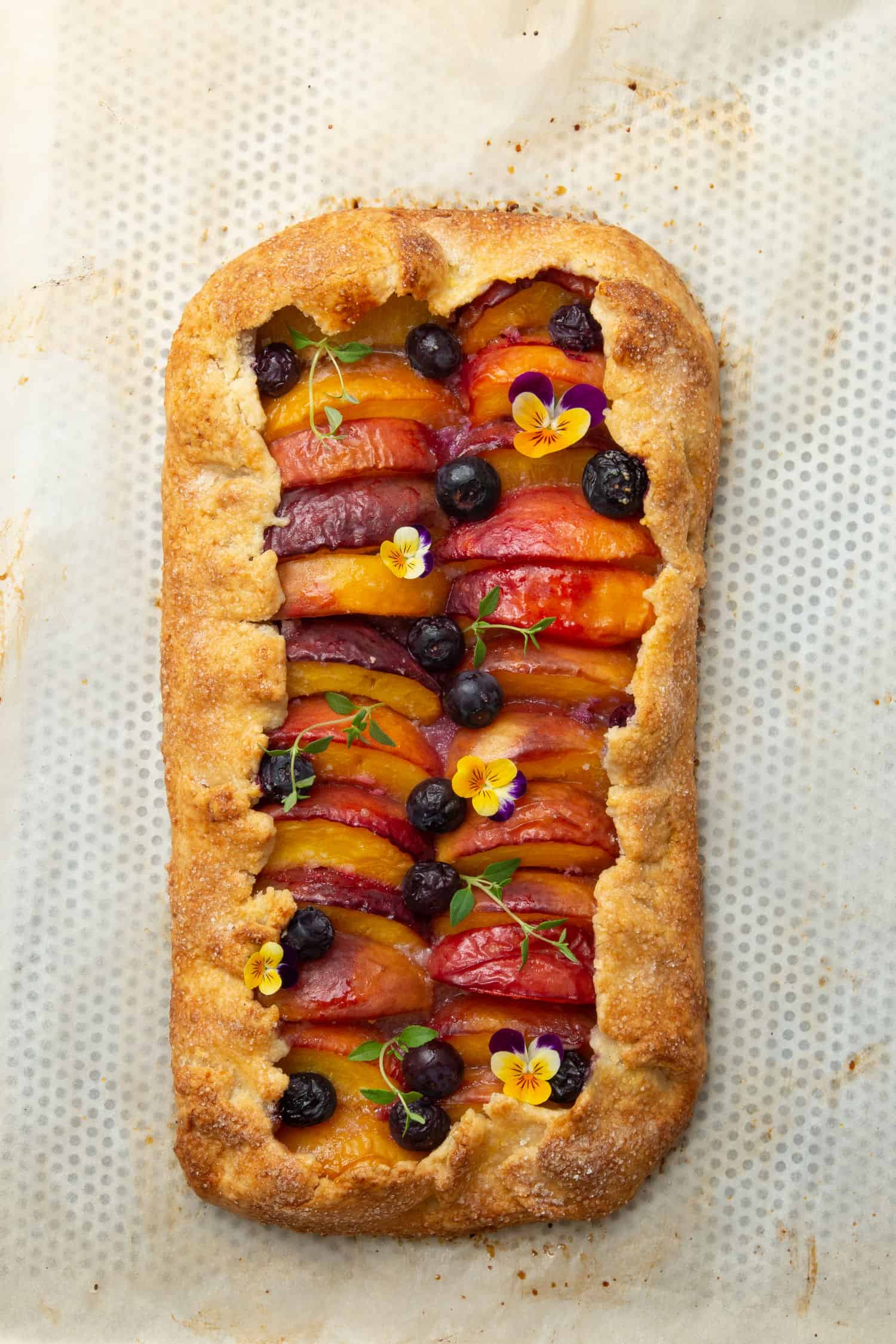 Baked and decorated Peach galette on a baking tray.