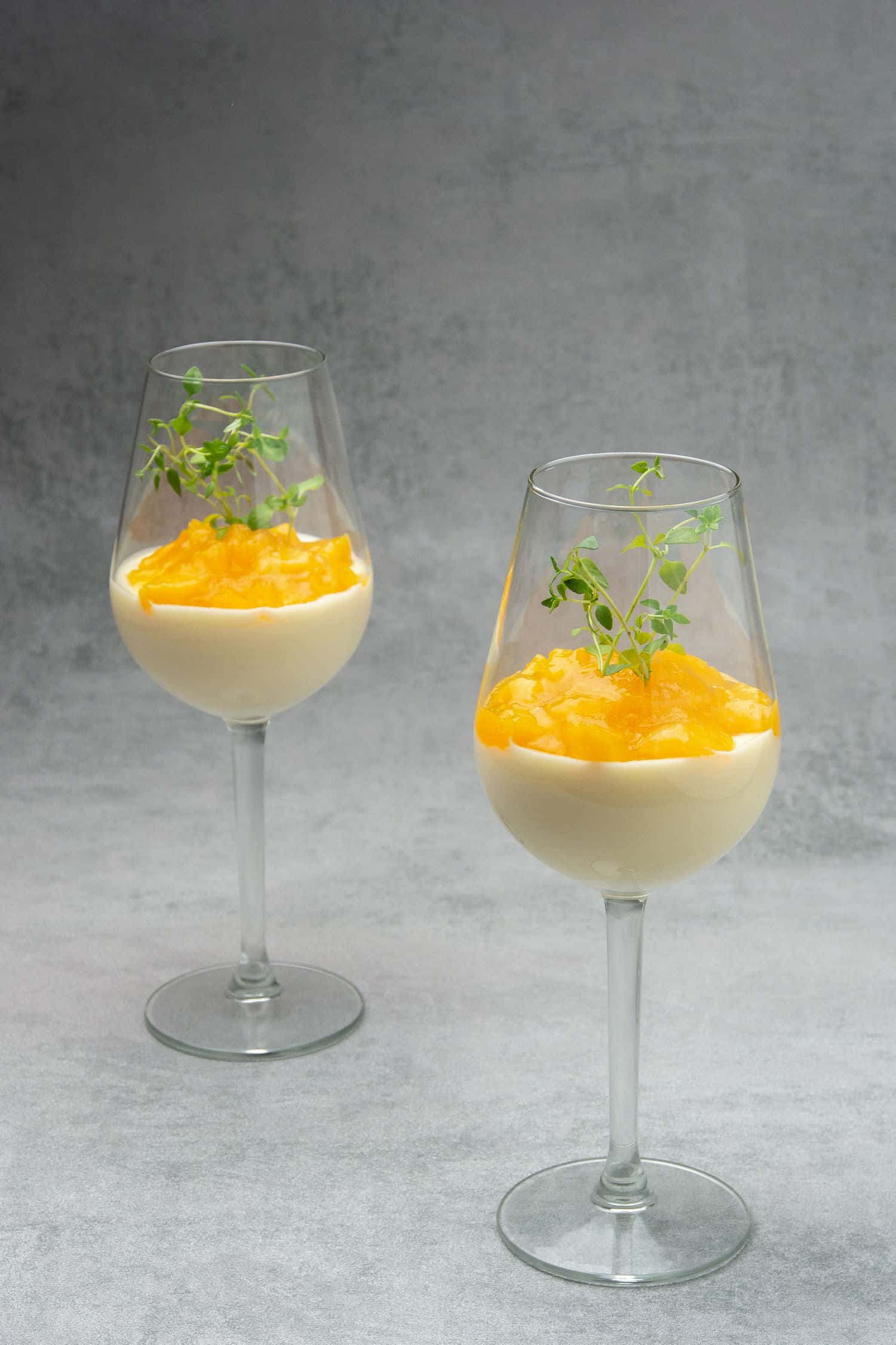 Two glasses of Wine mousse Parfait with peach with a gray background.