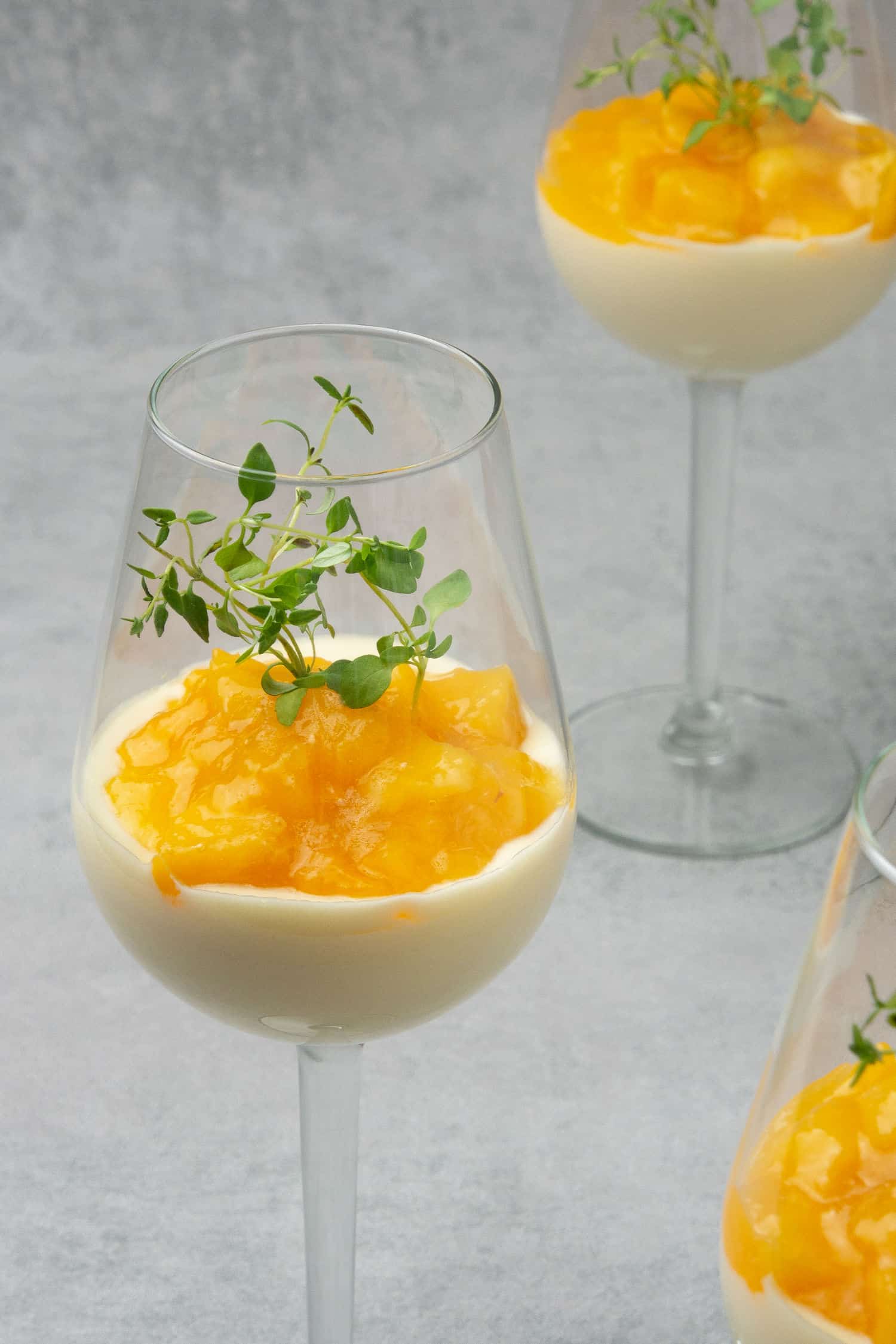 3 glasses of Wine mousse Parfait with peach on a gray table top.