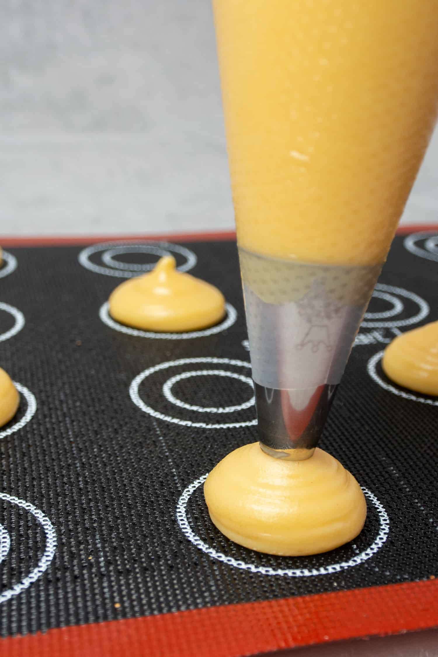 Piping the choux buns onto a perforated baking mat. 
