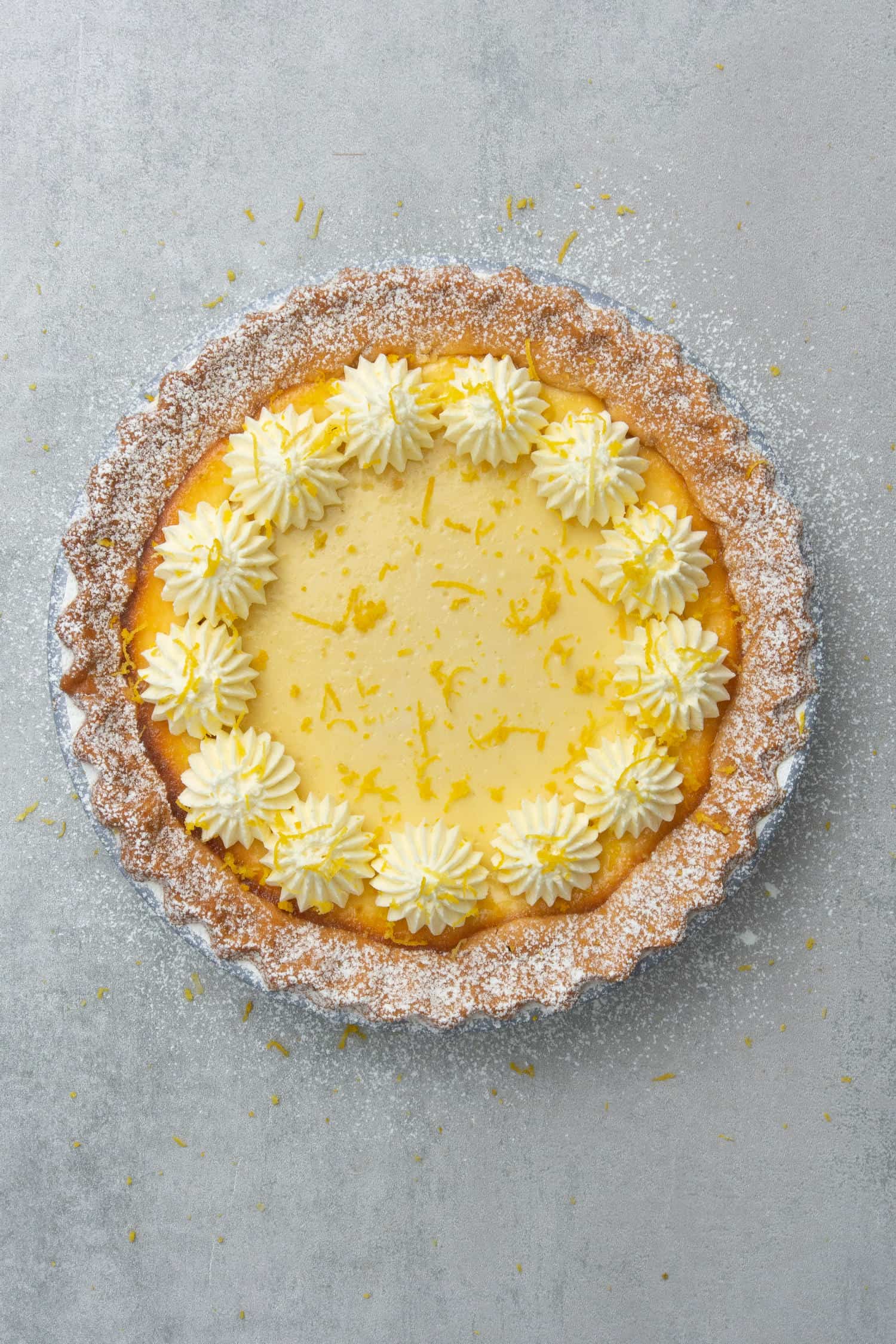 Ricotta pie decorated with whipped cream and lemon zest
