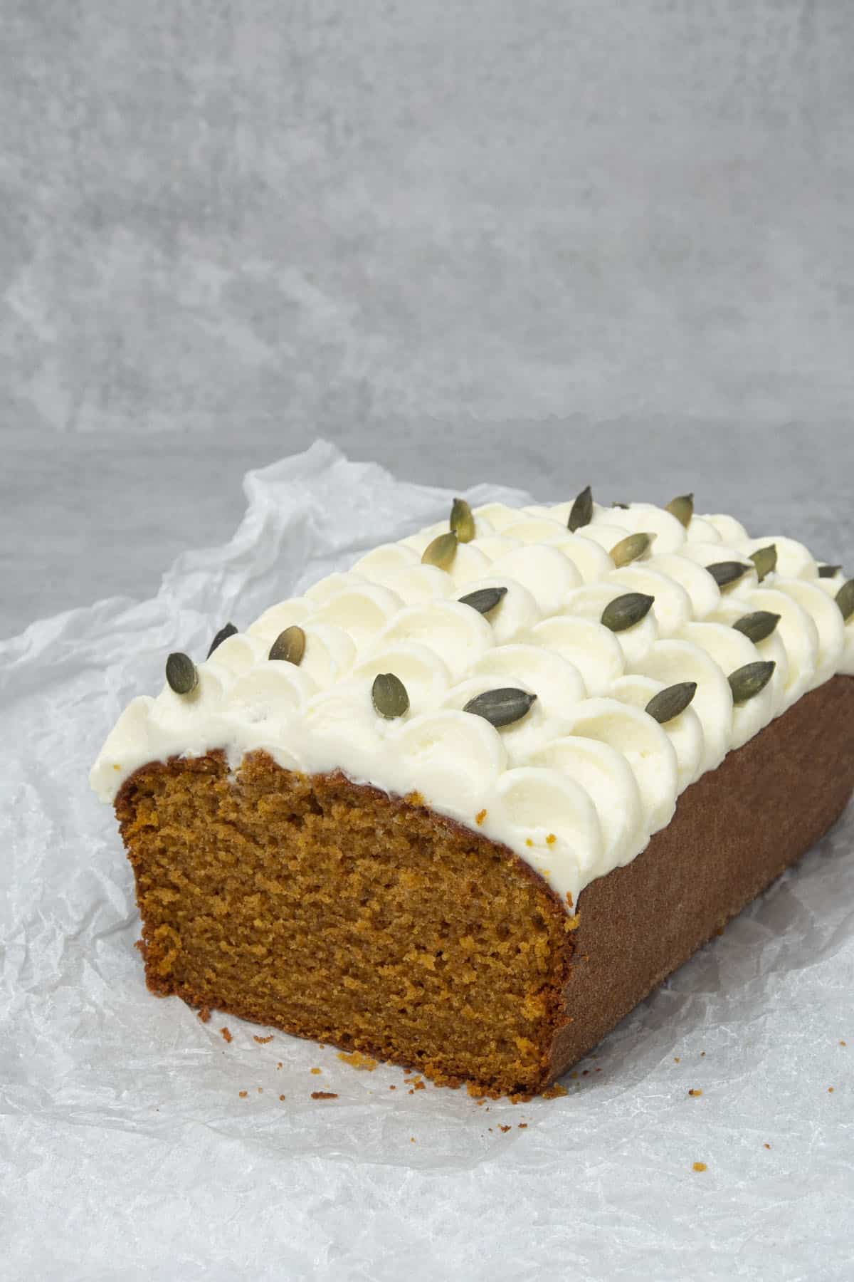 Pumpkin bread with cream cheese frosting on a white paper.