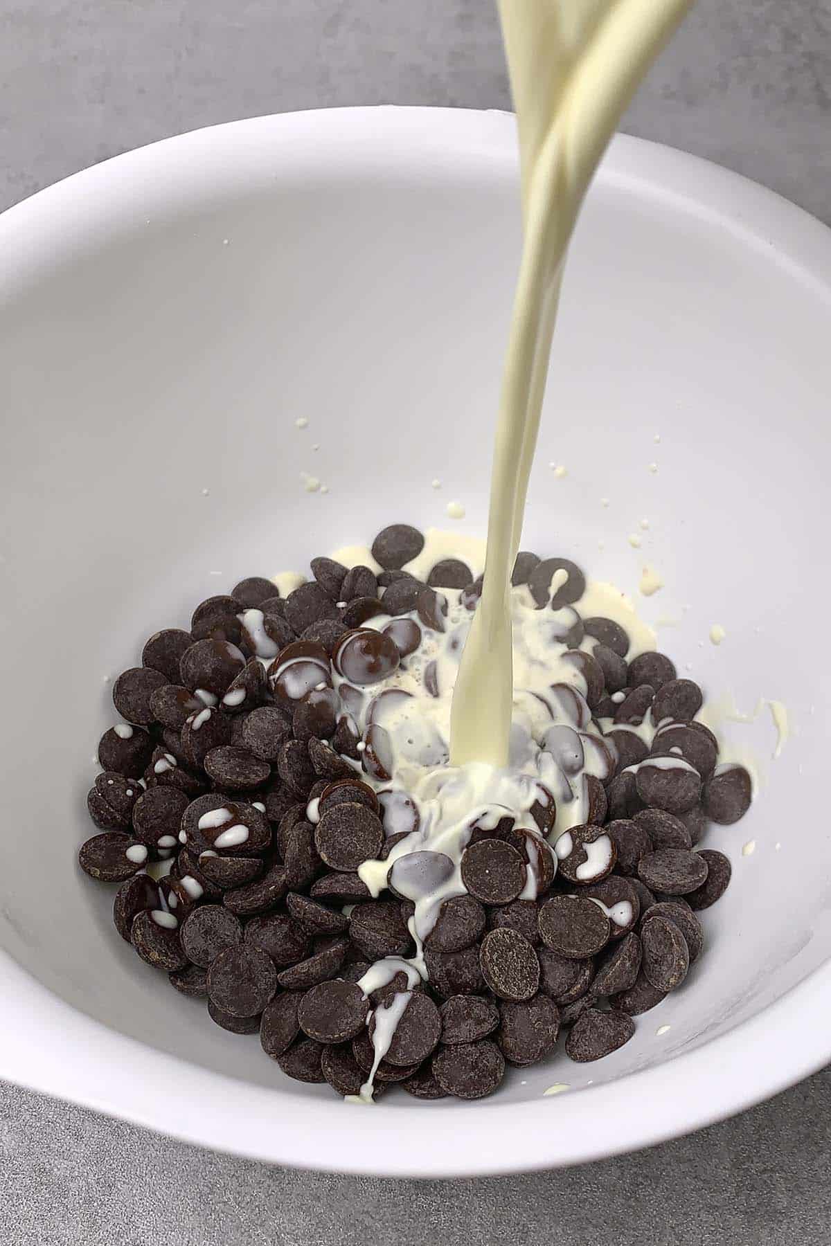Pouring hot cream on dark chocolate in a bowl