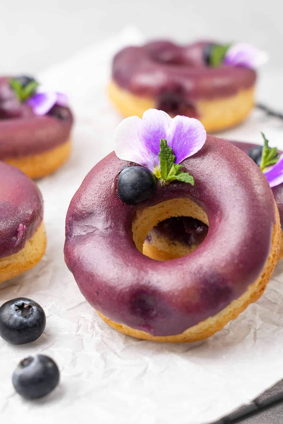 Blueberry baked donuts on a white baking paper  decorated with blueberries  