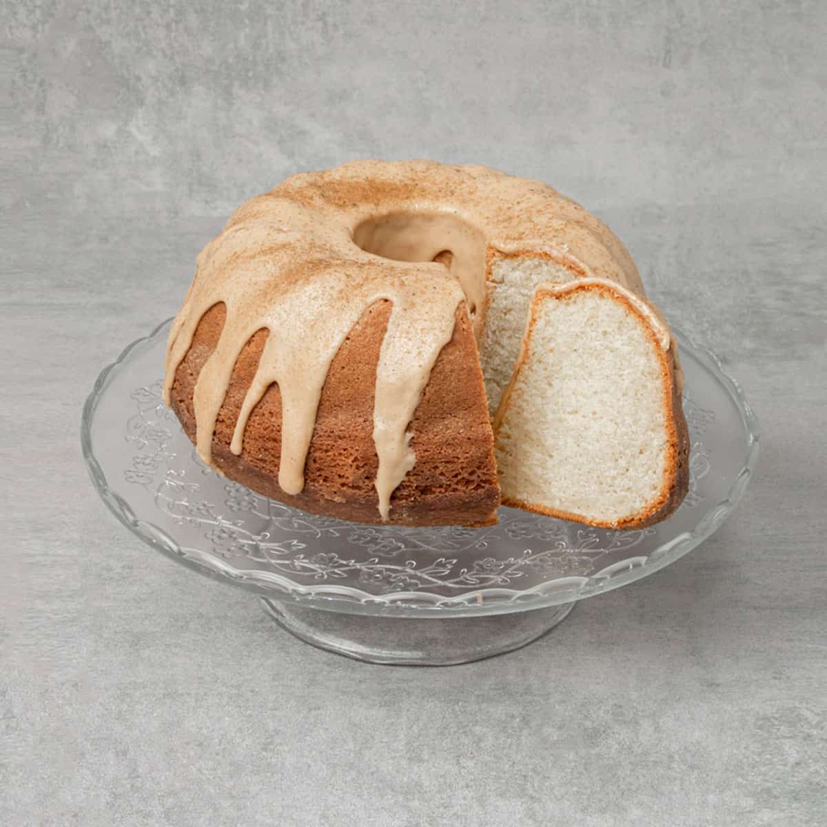 Cardamom cake sliced on a glass cake stand.