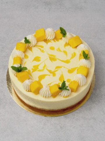 Mango mousse cake on a gold paper plate.