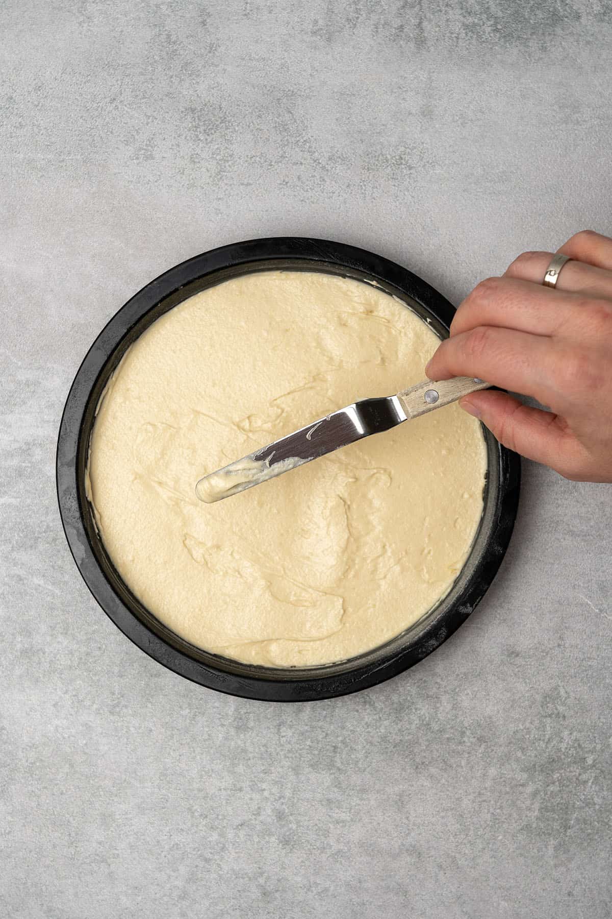 Smoothing the top of the sponge cake batter with an offset spatula before baking