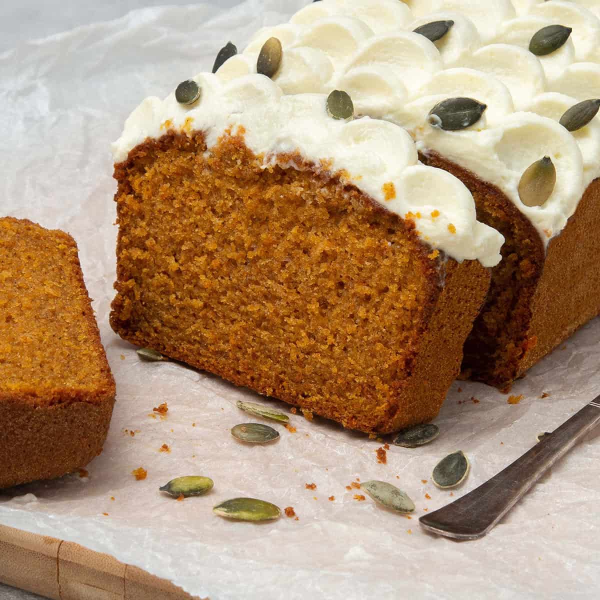 Pumpkin bread with cream cheese frosting cut into slices slices on a white paper.