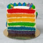 A half Rainbow cake on a golden paper plate.
