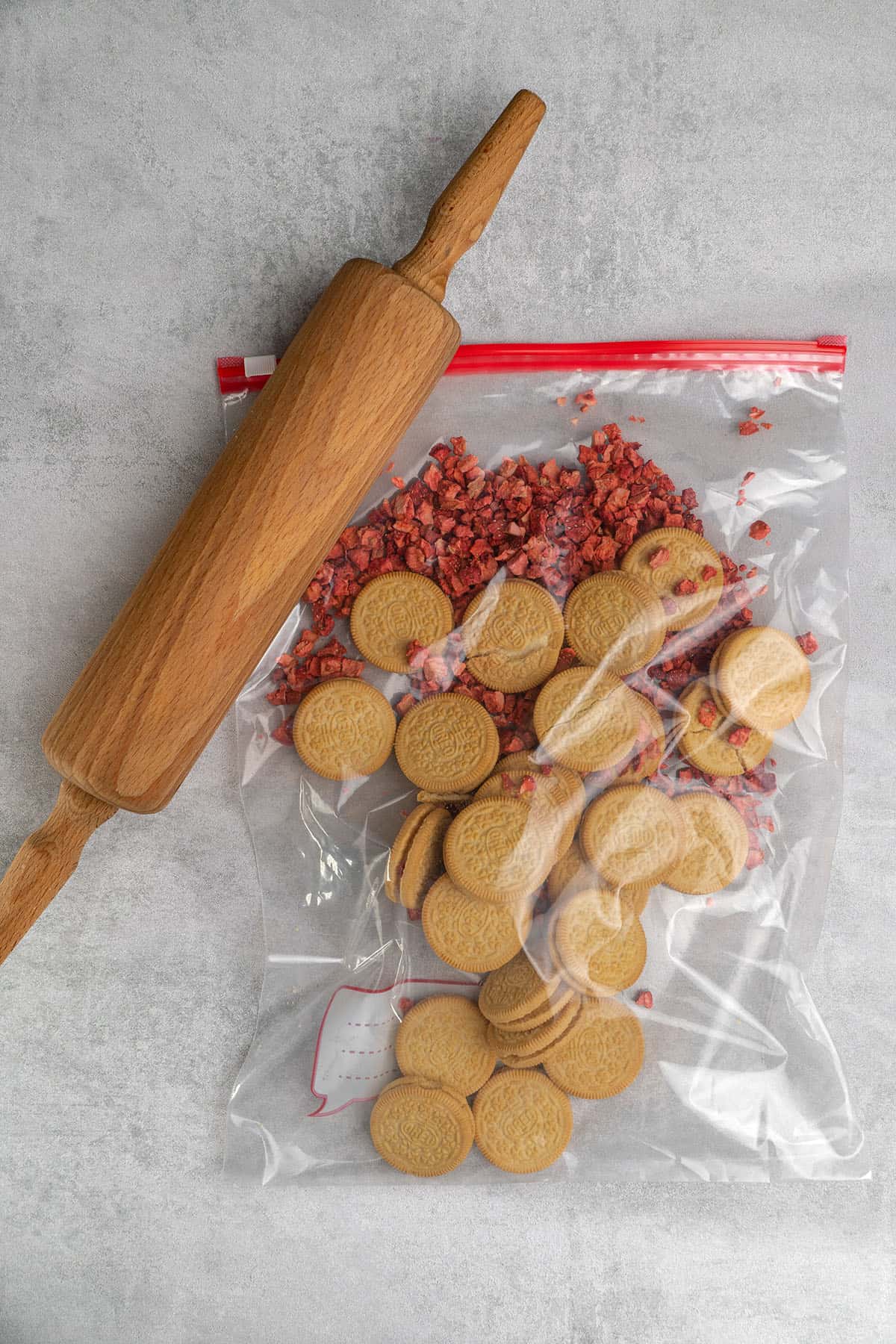 Freeze-dried strawberries and golden oreo in a plastic bag and a roller on top.