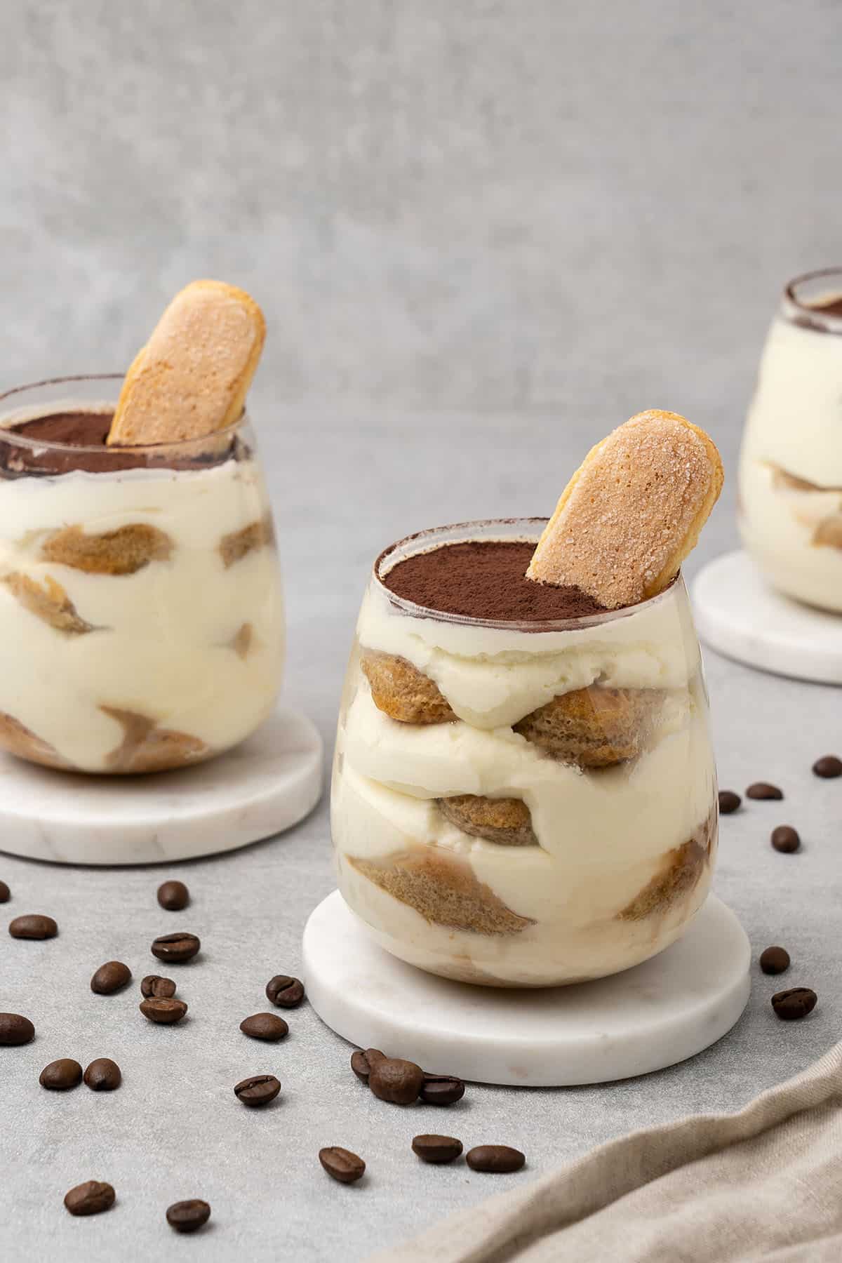 3 Mini tiramisu cups in a glass on a table top.