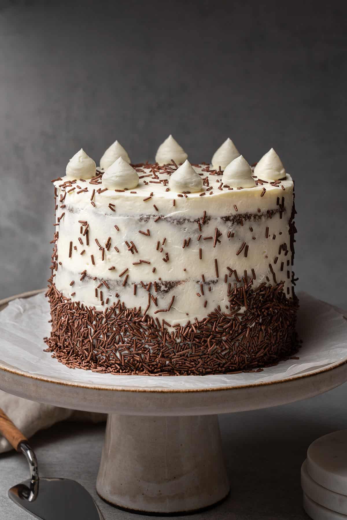Chocolate cake with cream cheese frosting on a cake stand.