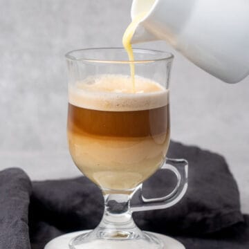Pouring white chocolate sauce into a cup of coffee.