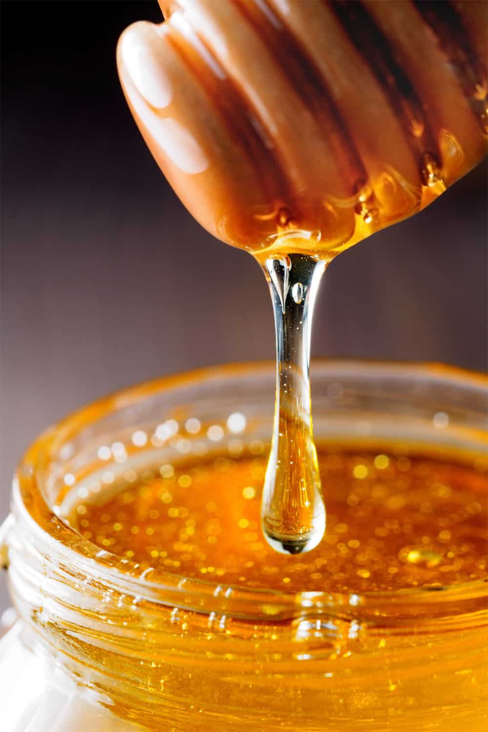 honey is dropping from a honey dripper.