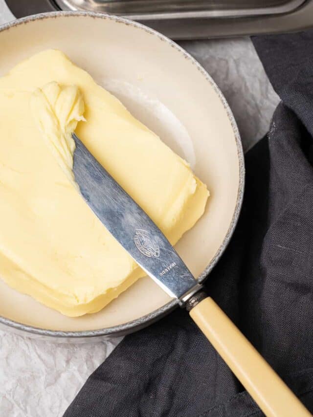 Homemade butter on a plate with a knife.