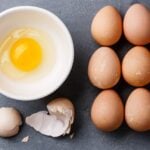 Eggs on a table and one cracked egg.