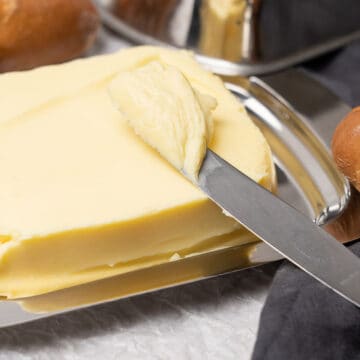 Scraping butter with a knife.