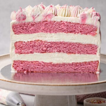 A half pink cake on a cake stand.
