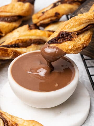 Nutella puff pastry twists dipping in chocolate cream.