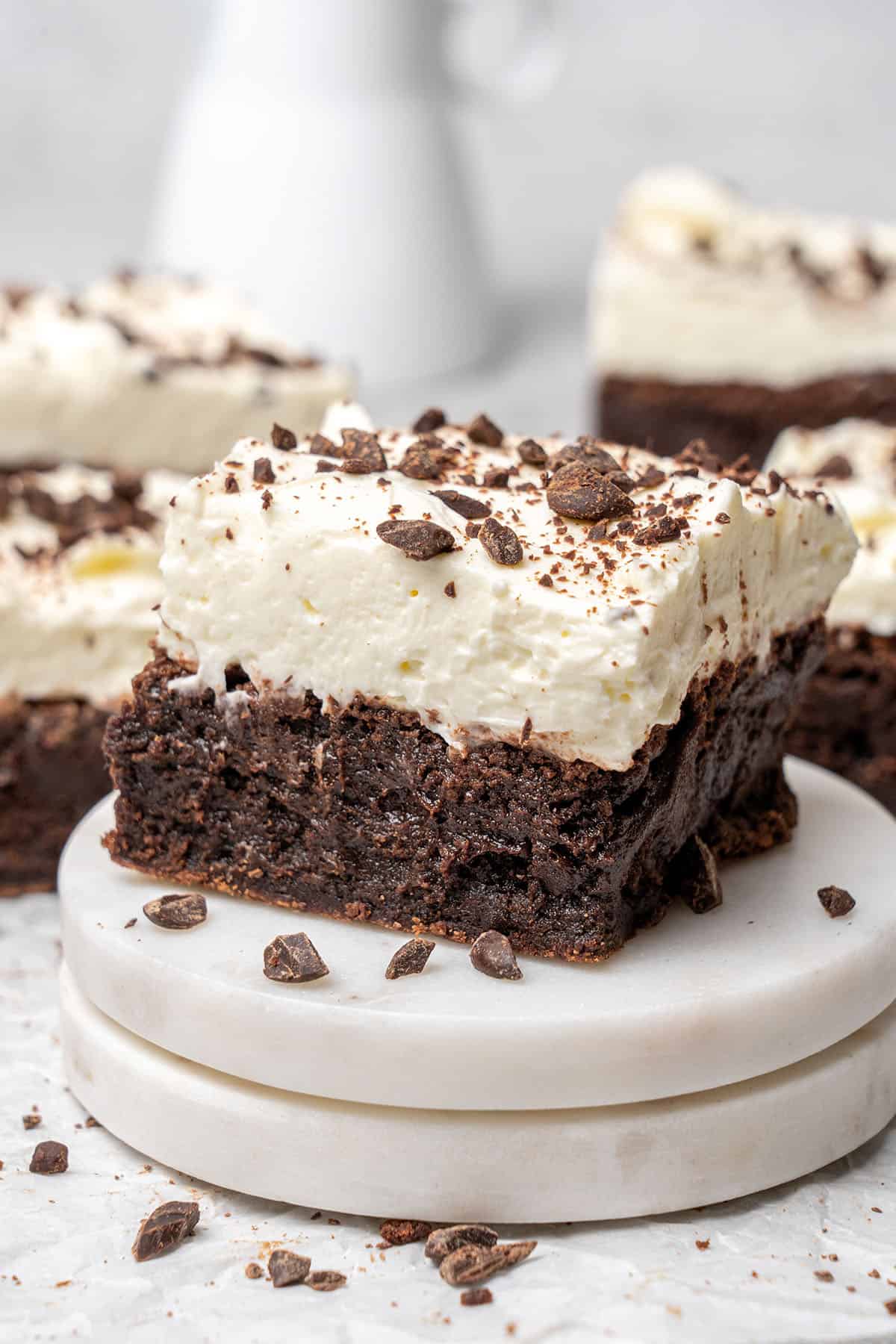 a brownie with cream cheese frosting on a cake stand.