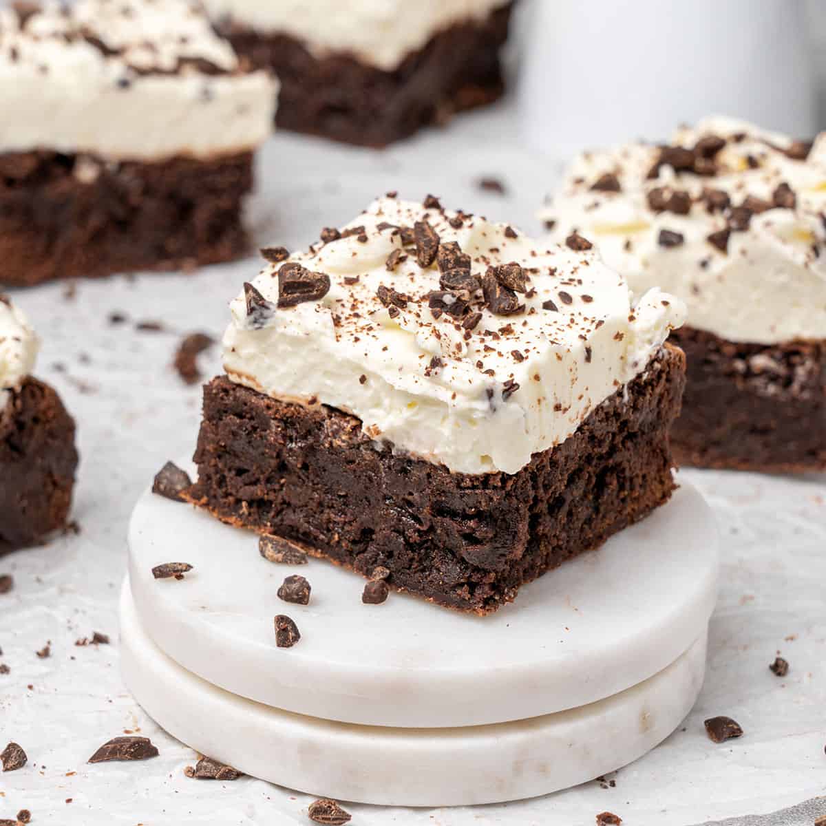 a brownie with cream cheese frosting on a cake stand.