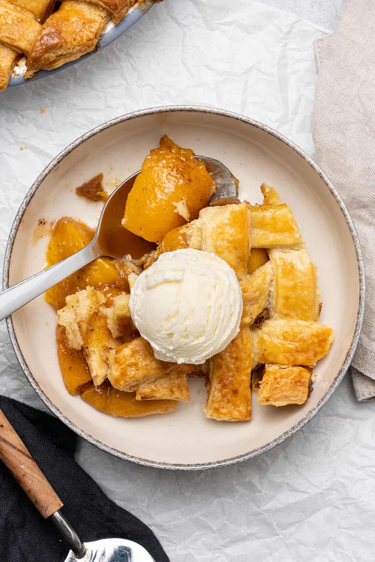 peach cobbler with pie crust and a scoop of ice cream.