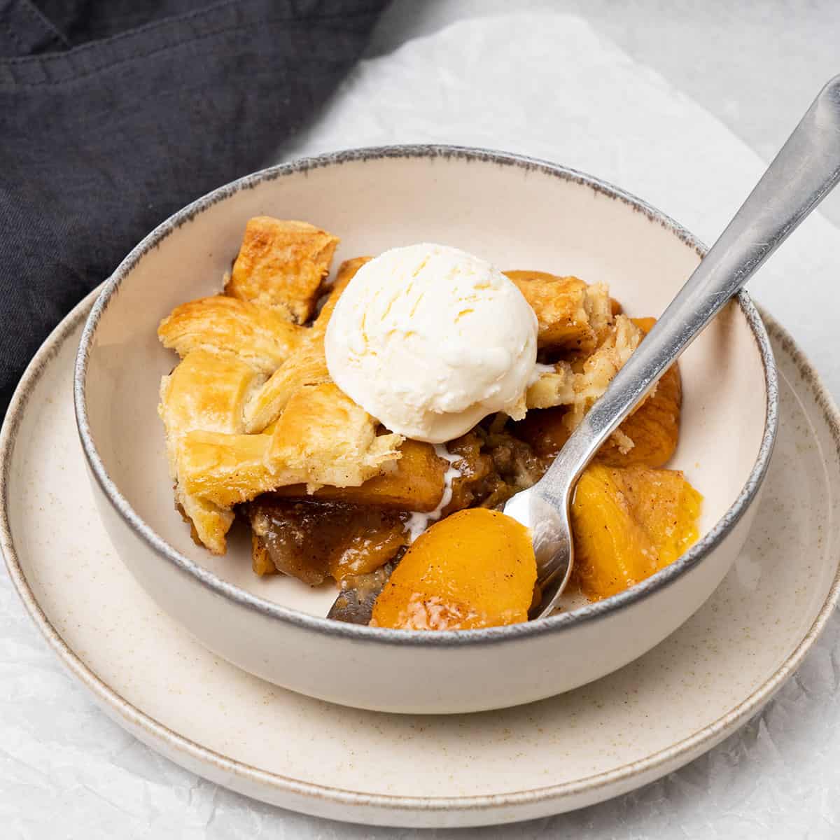 peach cobbler with pie crust and a scoop of ice cream.