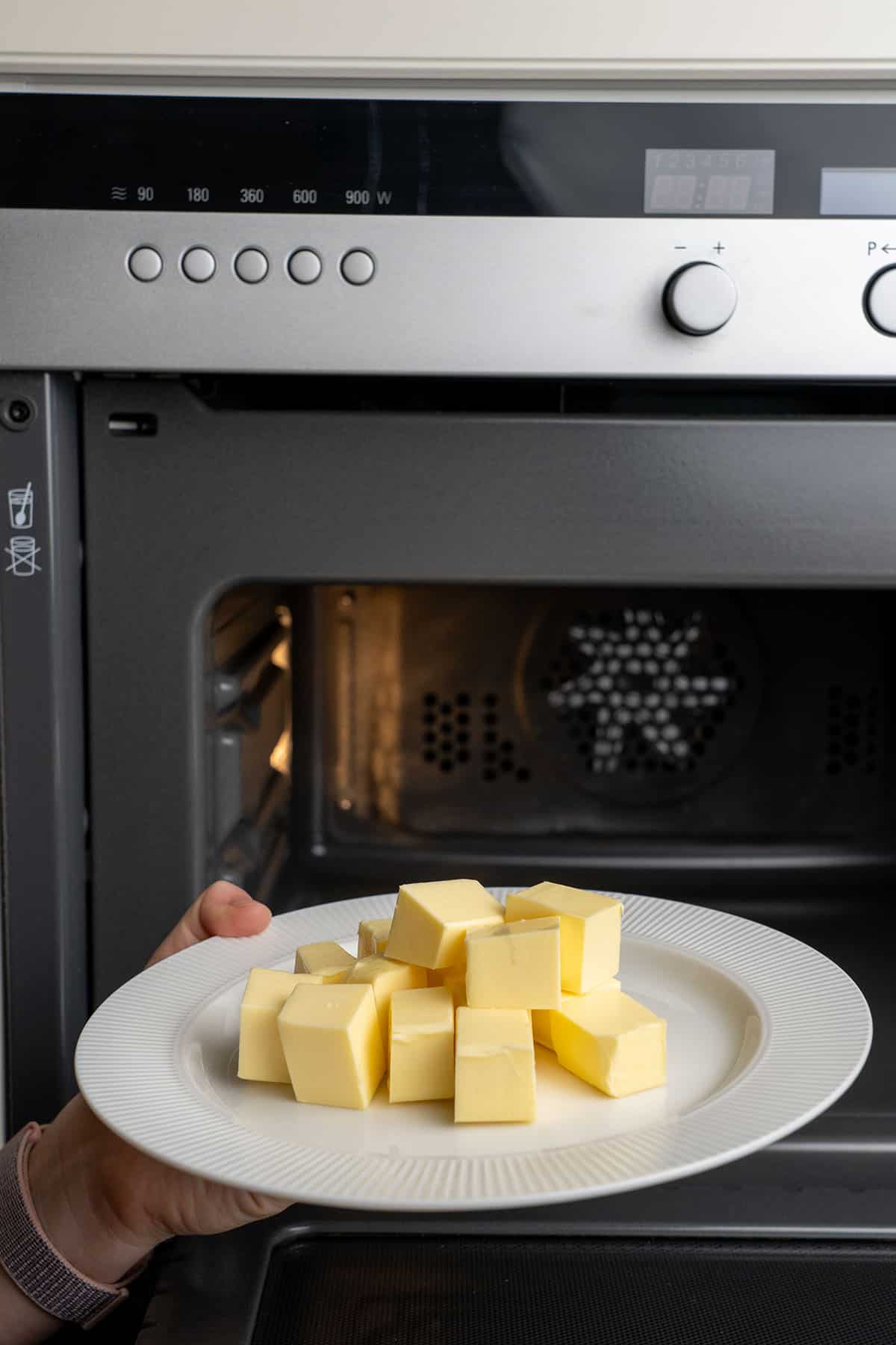 Putting butter cubes on a plate into a microwave.