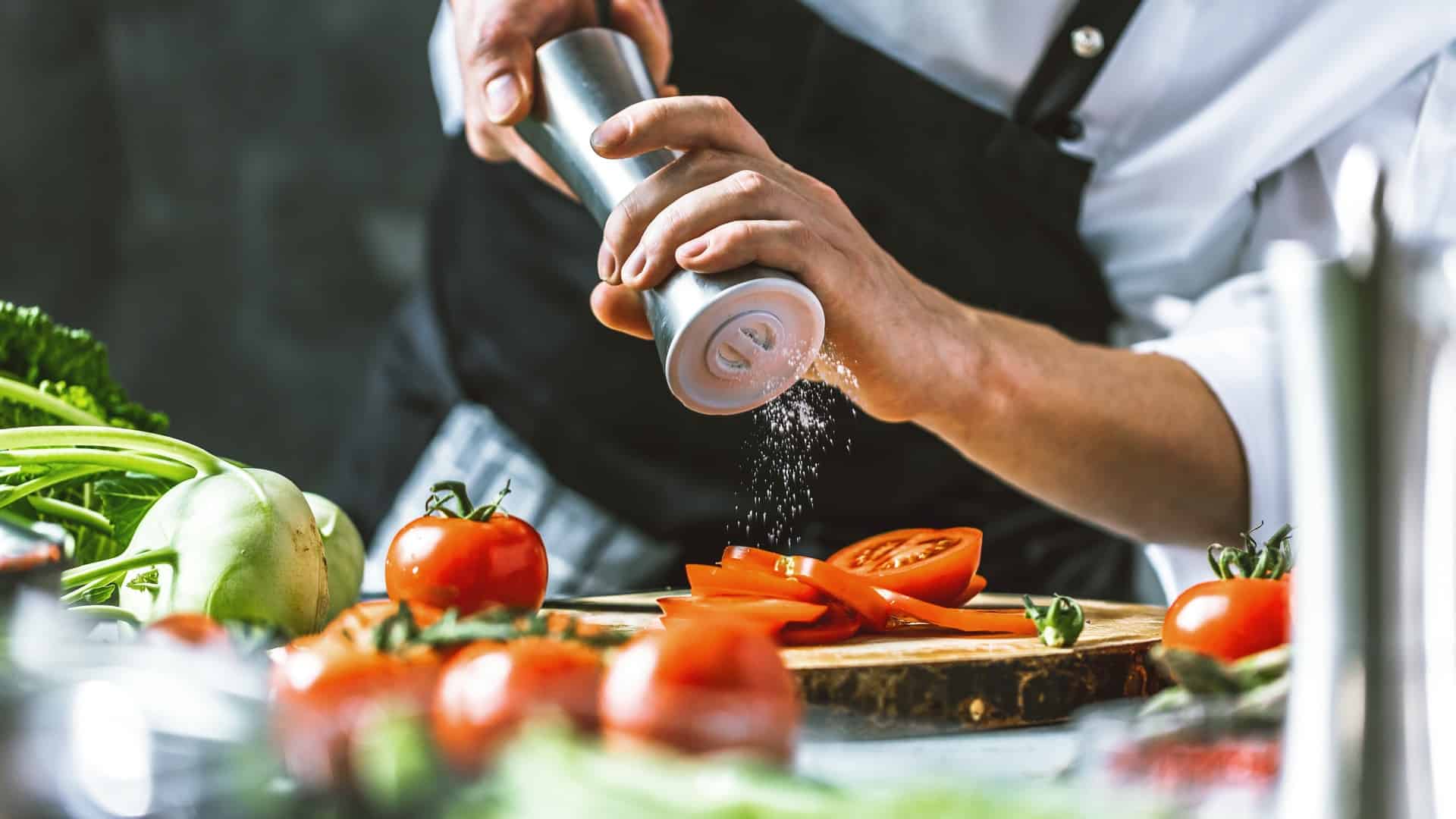 Chef grinding pepper on tomatoes