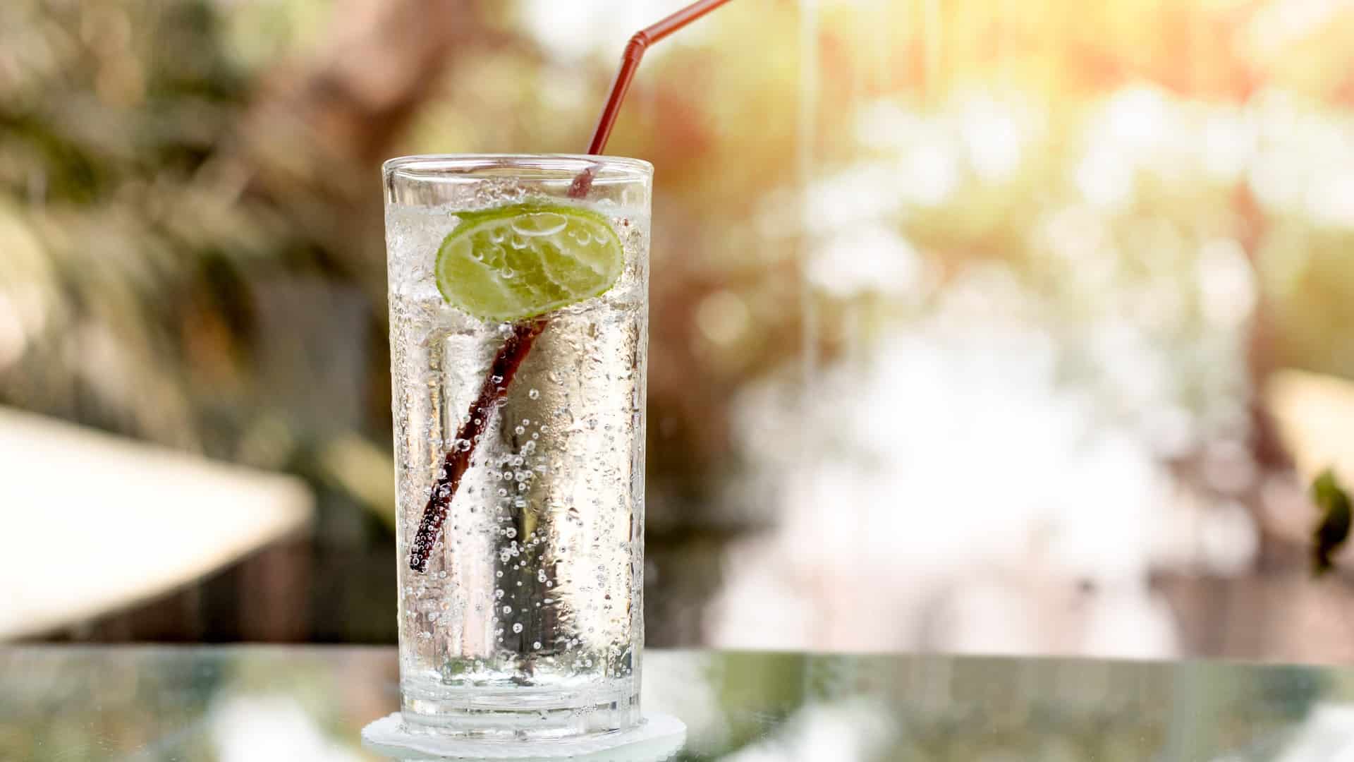 glass of seltzer with a lime and straw