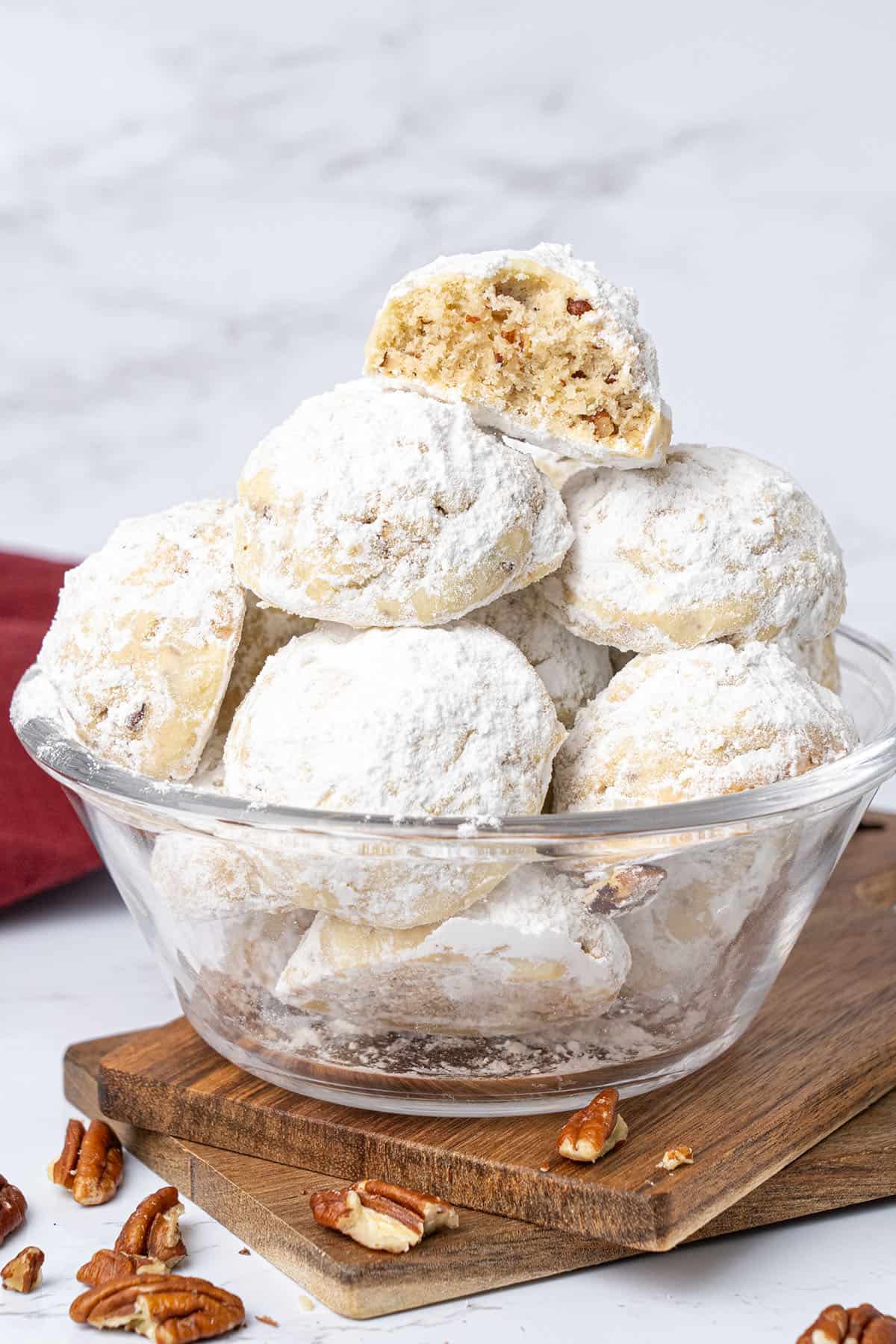 Pecan snowball cookies in a glass bowl.
