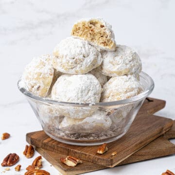 Pecan snowball cookies in a glass bowl.