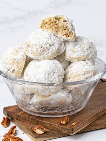 Pecan snowball cookies in a glass bowl.