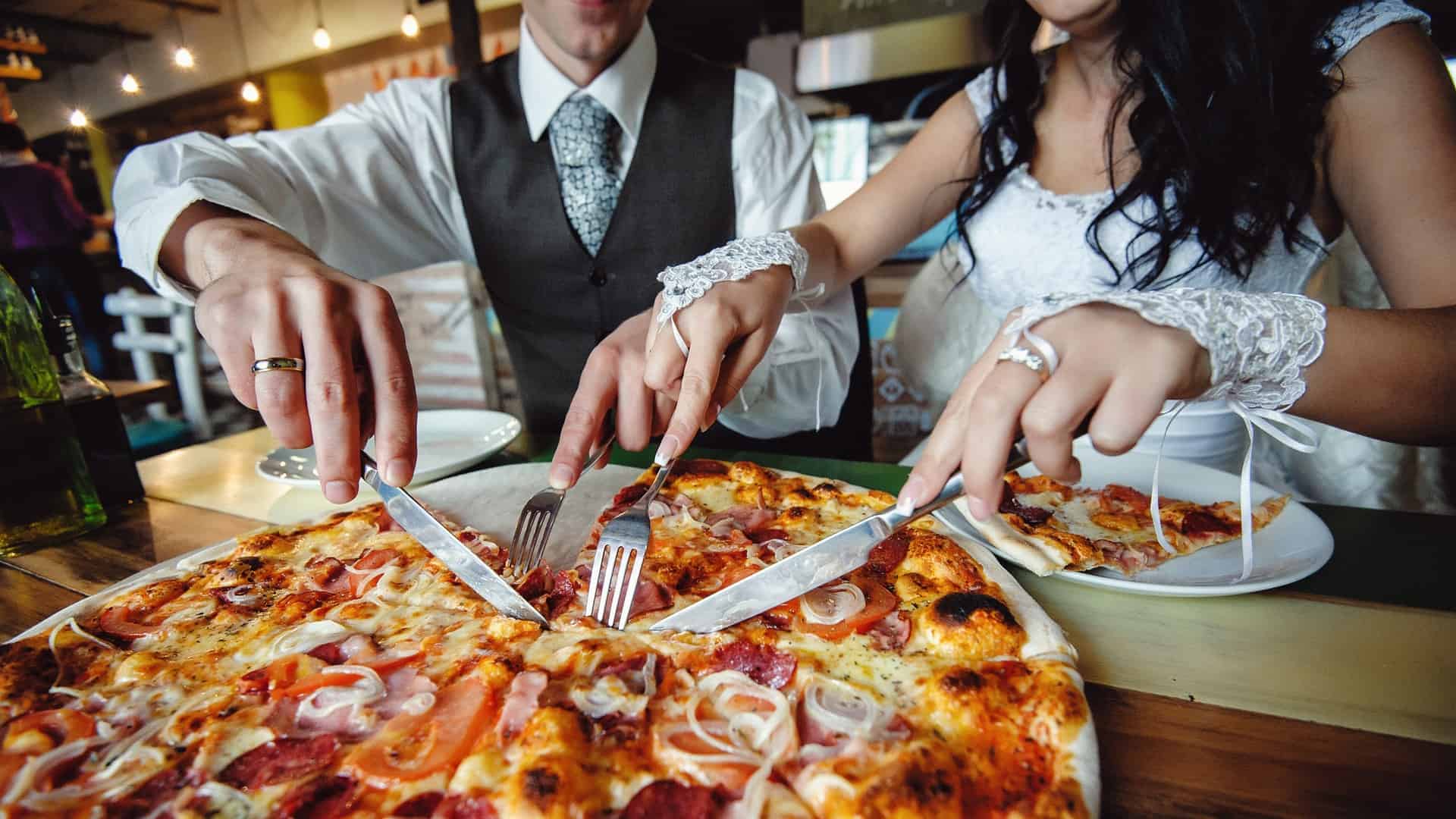 bride and groom cutting pizza