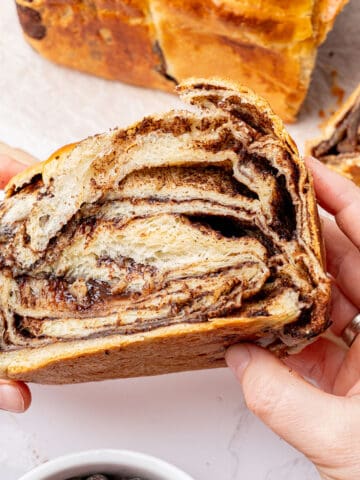 A hand holding a slice of chocolate brioche.