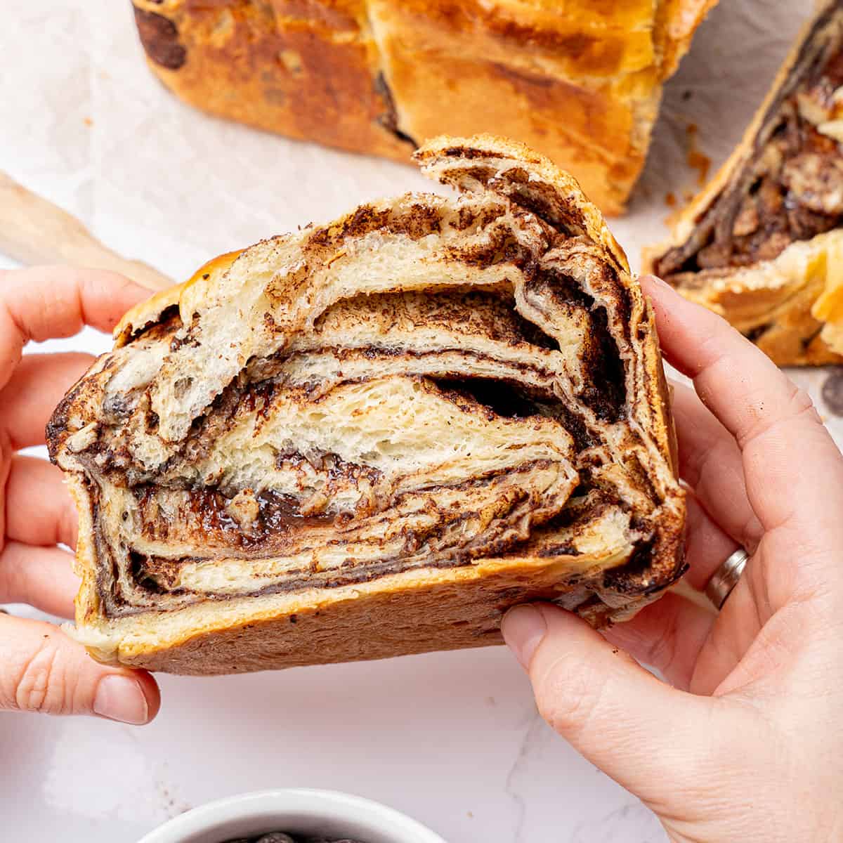 A hand holding a slice of chocolate brioche.